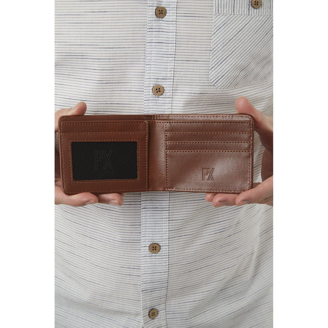 A person holds open their Easy Vegan Leather Bi-Fold Wallet from Yellow Florence against their striped shirt, highlighting their commitment to conscious consumerism with this eco-friendly accessory.