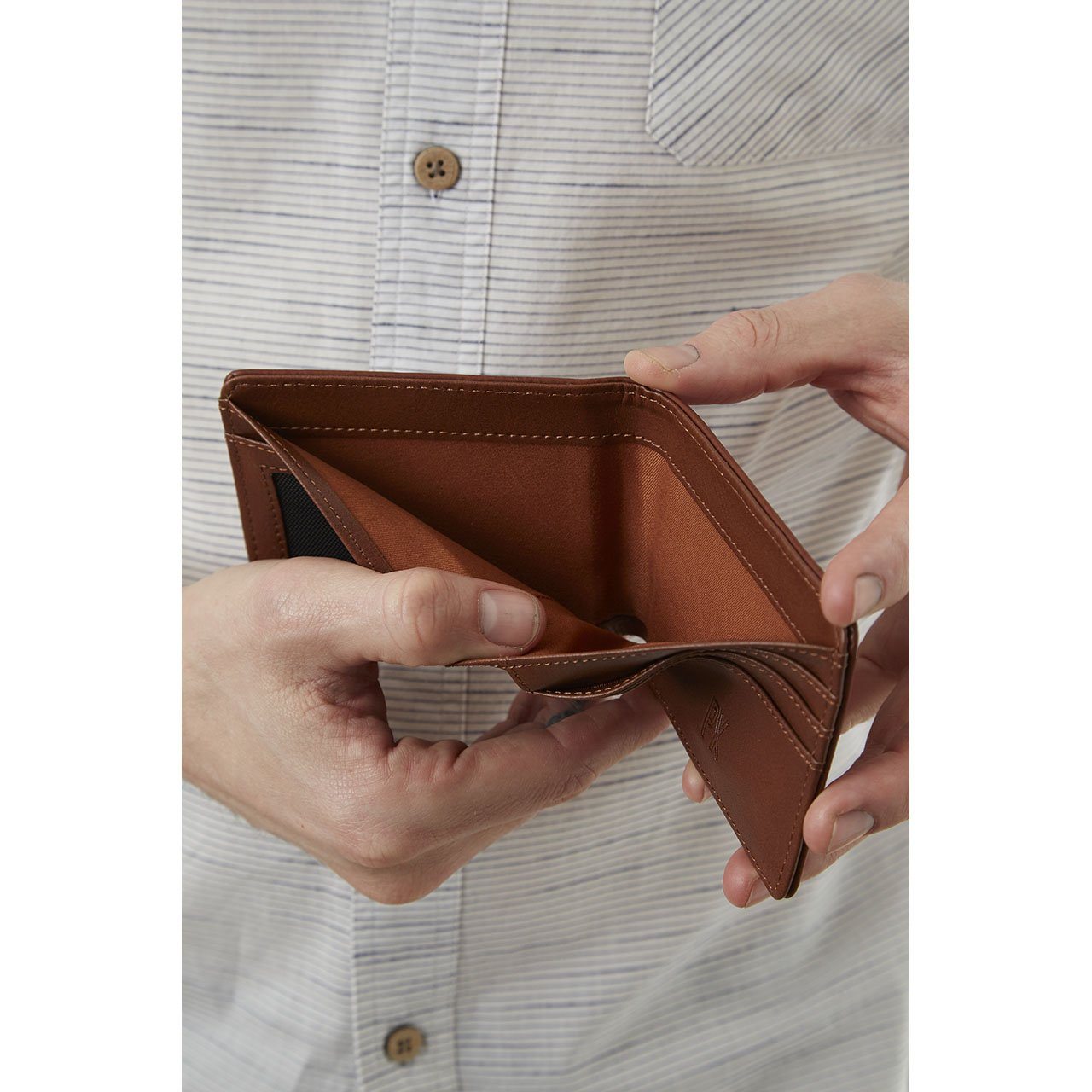 A person holds an open Easy Vegan Leather Bi-Fold Wallet from Yellow Florence, an empty brown wallet crafted from vegan leather, making it a perfect choice for the conscious consumer seeking an eco-friendly accessory.