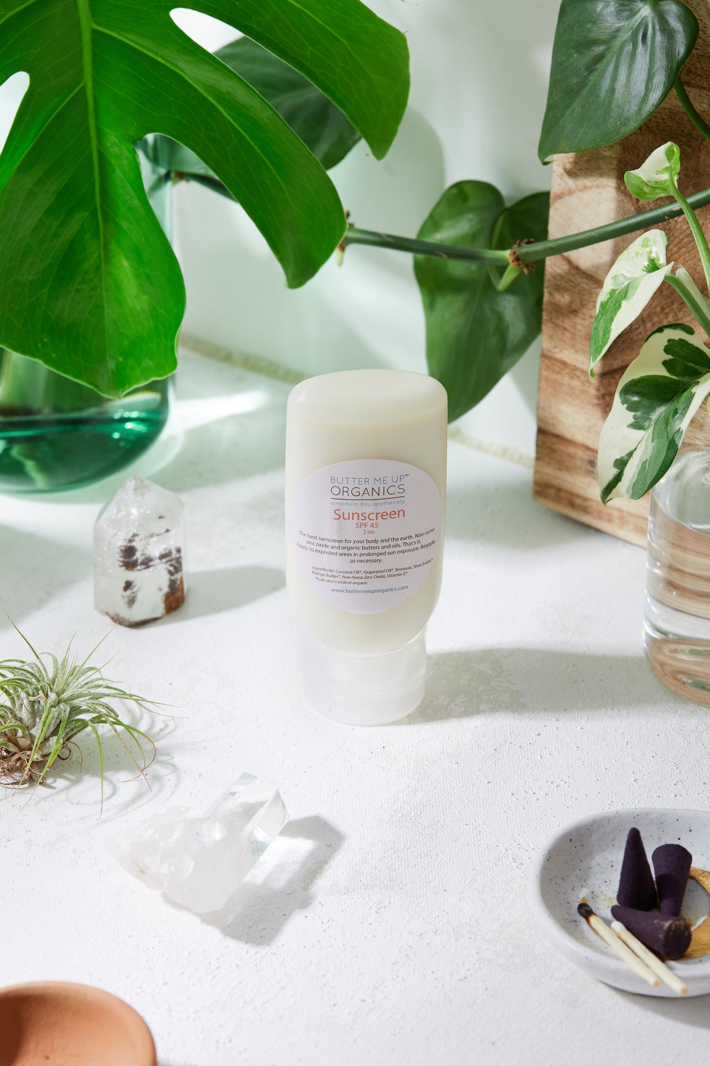 A white table with plants and White Smokey zinc oxide sunscreen on it.