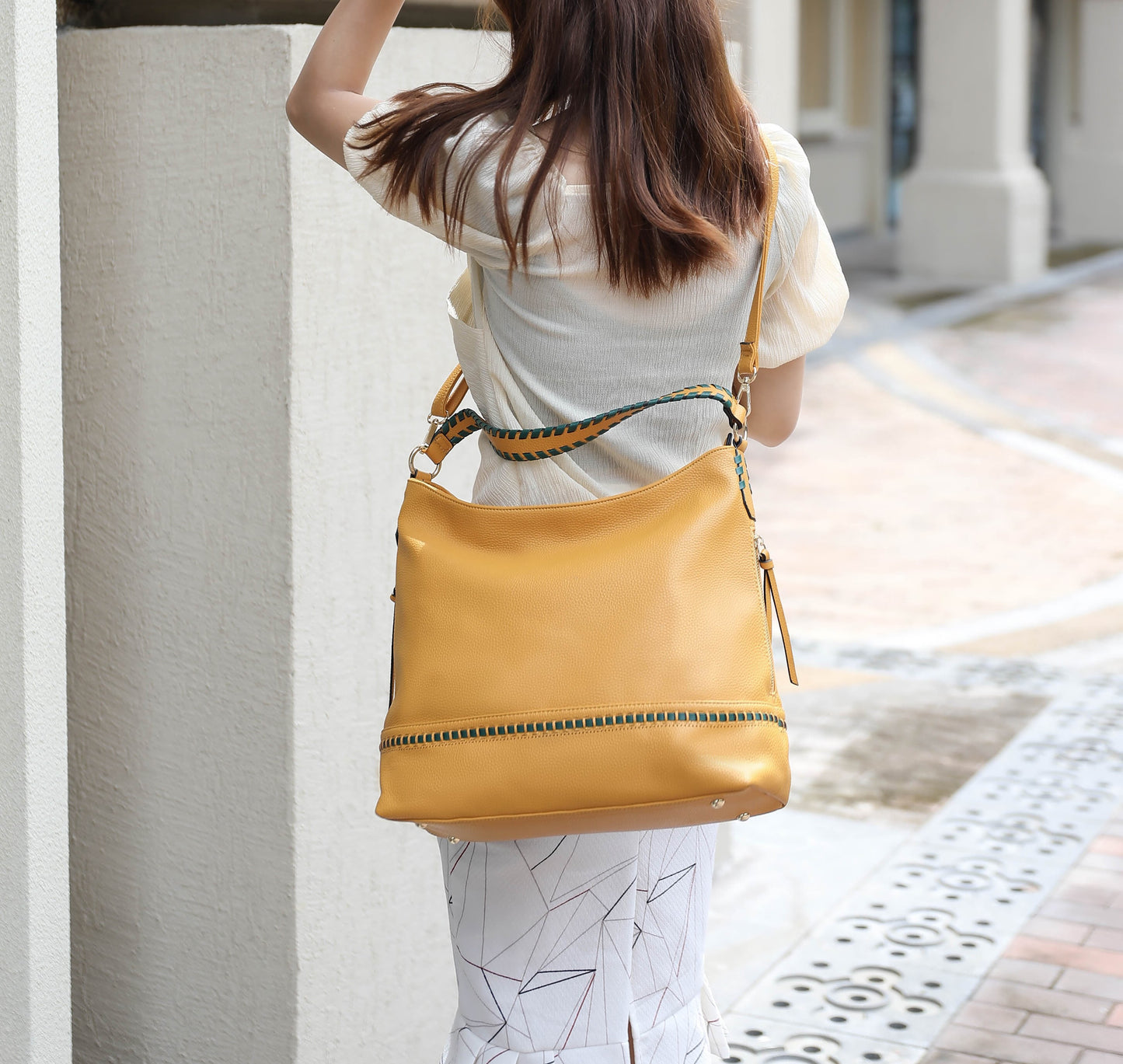 A woman is holding a Pink Orpheus Blake two tone whip stitches Vegan Leather Shoulder bag with Wallet.