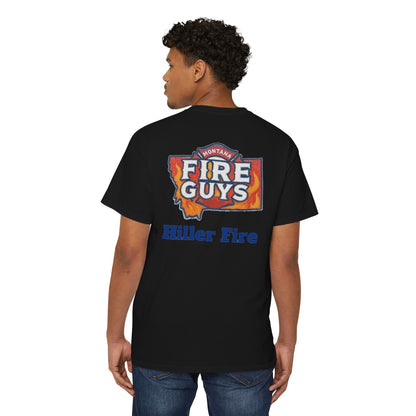 A man wears the Unisex Heavy Cotton Pocket Tee from Printify, featuring "Montana Fire Guys" and "Hiller Fire" on its black fabric, blending style and comfort for firefighters and outdoor enthusiasts.