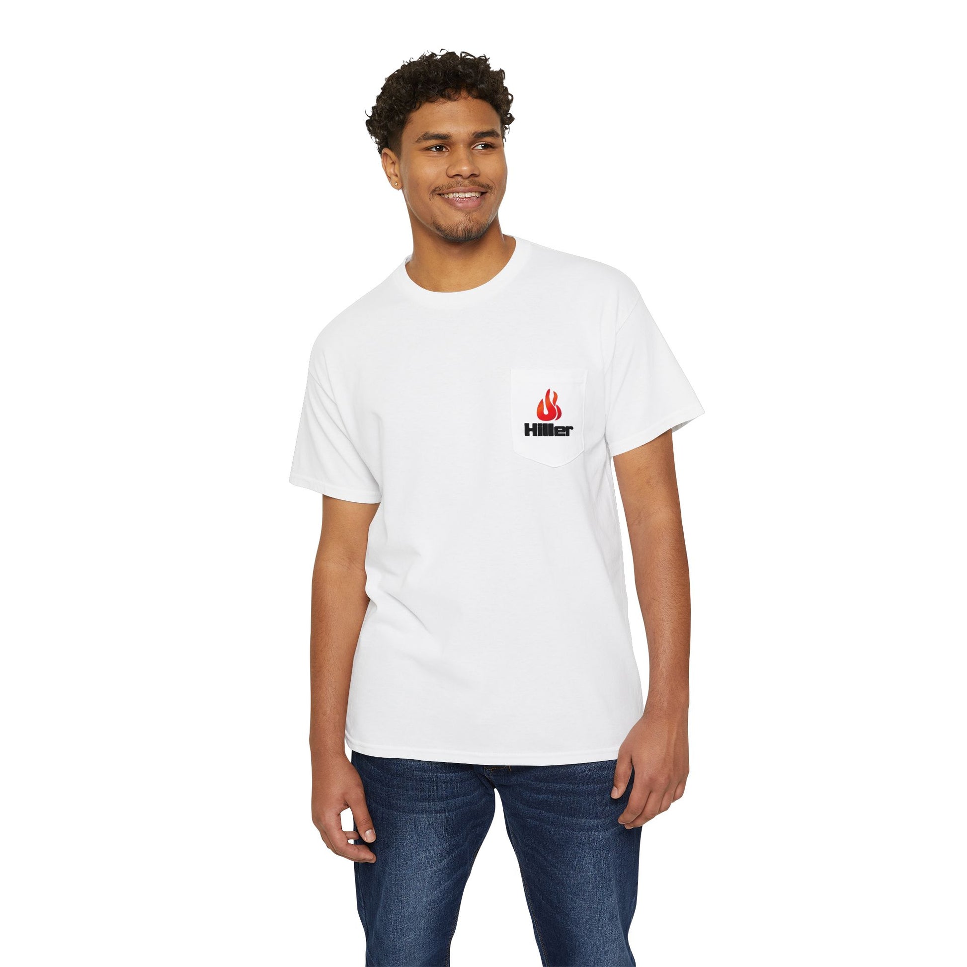 A man in a Printify Unisex Heavy Cotton Pocket Tee featuring the Hiller Fire Guys graphic with a red flame logo on the left chest pocket smiles in blue jeans against a white background, ready for casual outings.