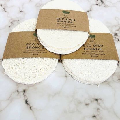 Three eco-friendly plant loofah dish sponges with White Smokey Organic Solid Dish Soap, packaged in brown recycled paper on a marble surface for a zero-waste kitchen.