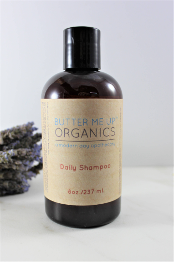 A brown bottle of White Smokey's Organic Daily Shampoo with a beige label, standing next to dried lavender on a white background.