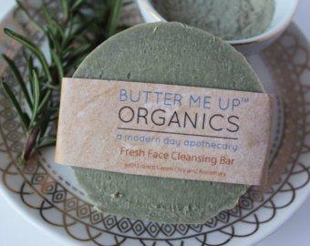 Organic facial cleansing bar with French Green Clay from White Smokey displayed on a plate with herbs in the background.