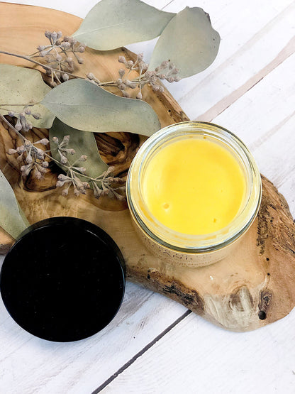 A jar of White Smokey Sea Buckthorn Facial Moisturizer on a wooden cutting board.