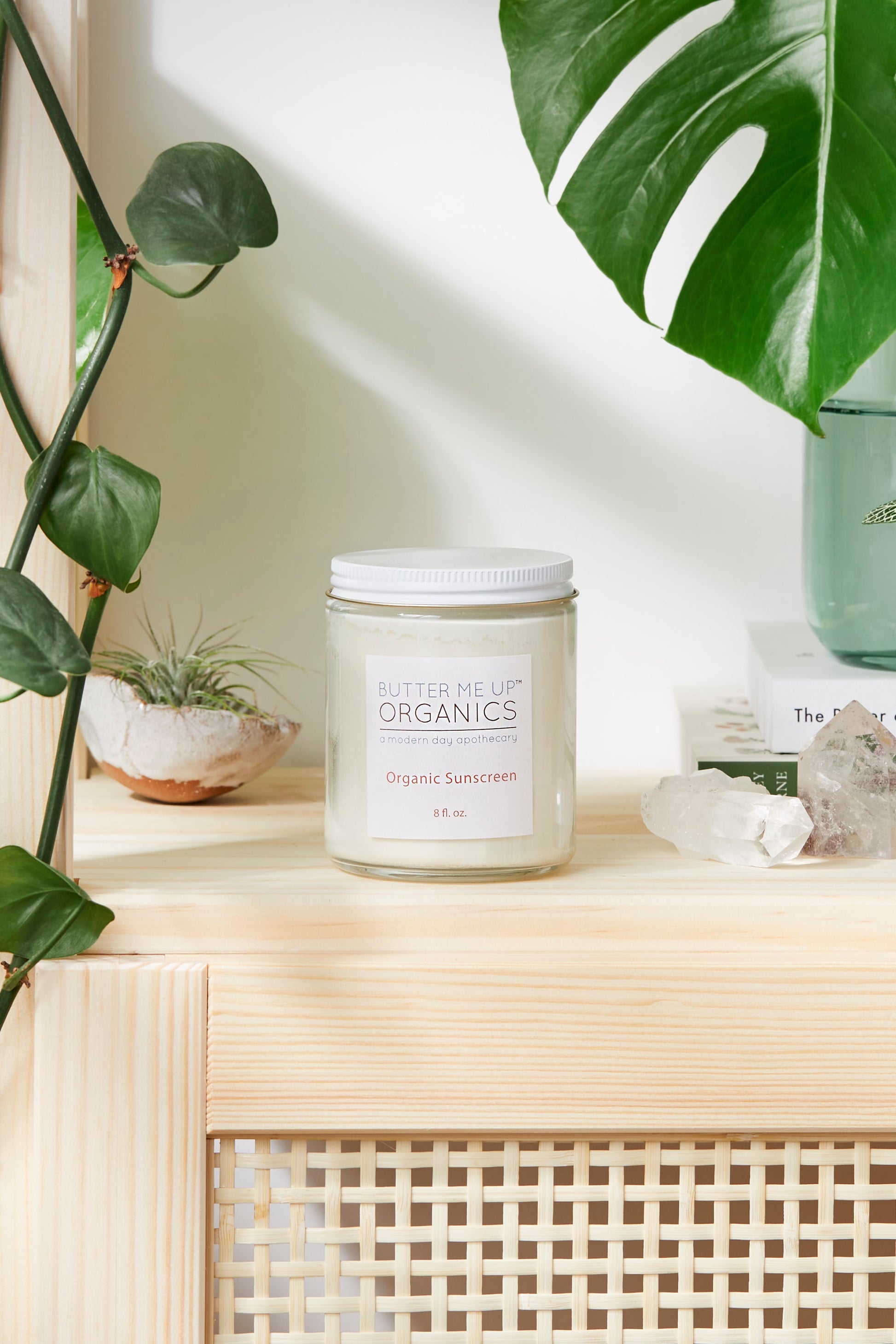 A Natural Organic Sunscreen by White Smokey sits on a wooden shelf next to a candle.