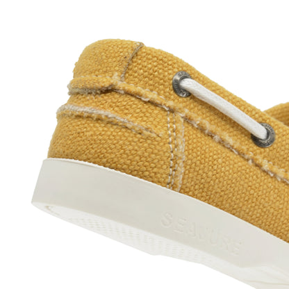 Close-up of the heel of a yellow fabric Women Hemp & Vegan Boat Shoe Saharun with white stitching, white sole, white lace, and the brand name "Amethyst Hestia" embossed on the side of the sole. Crafted with sustainability in mind, these shoes feature premium hemp for an eco-friendly choice.