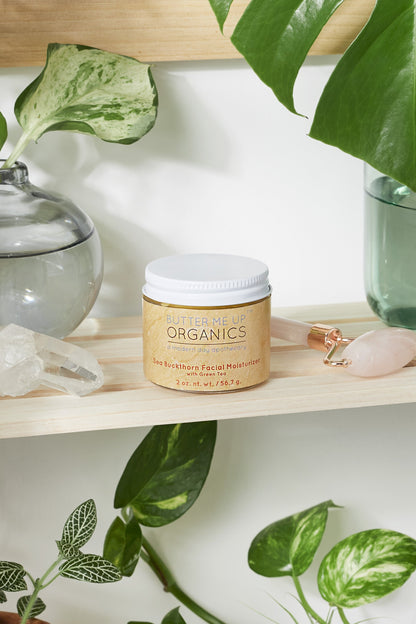 A jar of White Smokey organic anti-aging body butter sits on a shelf next to plants.