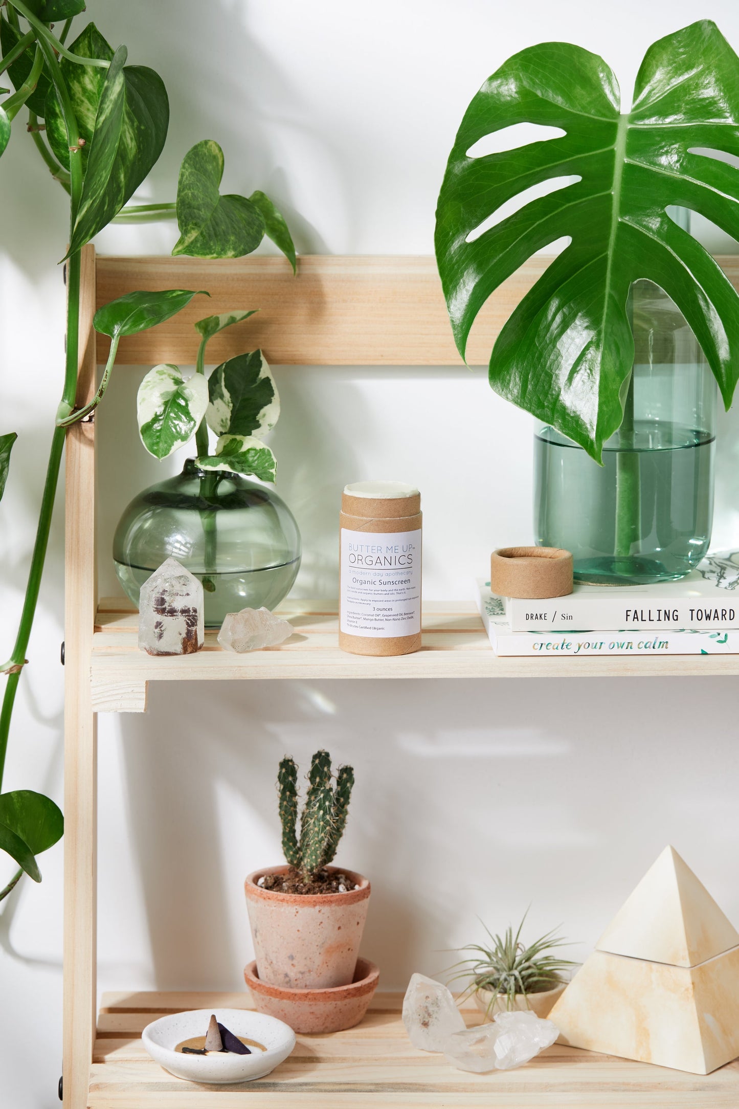 A shelf with White Smokey Natural Organic Sunscreen, books, and other items on it.