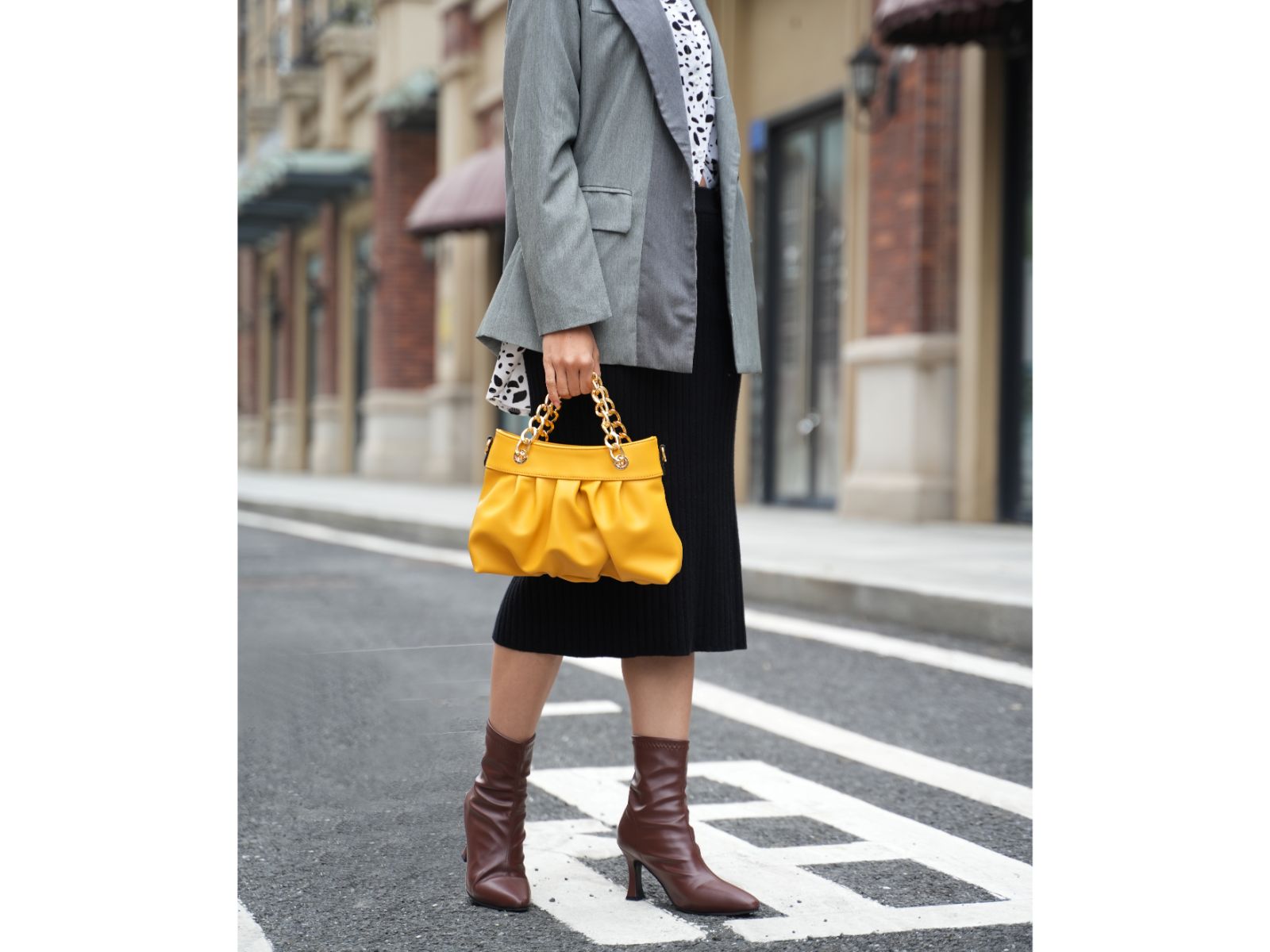 A woman in a gray blazer holding a Pink Orpheus Marvila Minimalist Vegan Leather Chain Ruched Shoulder Bag.