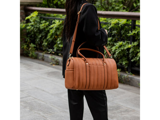 A woman is holding a Luana Quilted Vegan Leather Women's Duffle Bag by Pink Orpheus.