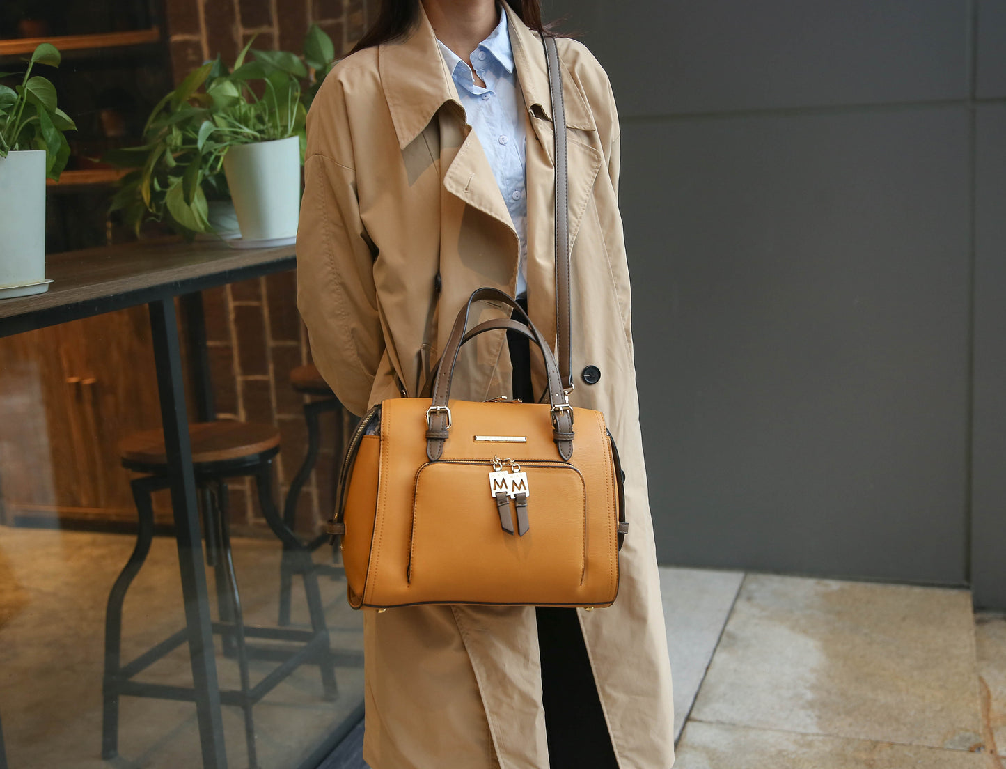 A woman in a trench coat holding a Pink Orpheus Elise Vegan Leather Color-block Women Satchel Bag.