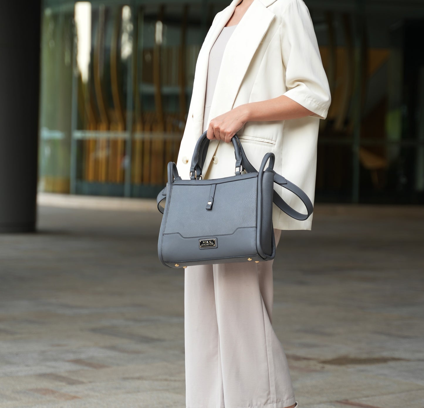 A woman holding a Pink Orpheus Melody Vegan Leather Tote Handbag in front of a building, her everyday companion.