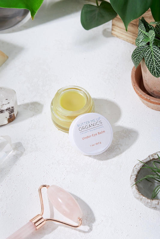 A jar of White Smokey lip balm and other items, including White Smokey caffeine-infused products for reducing puffiness under eyes (Caffinated Under Eye Balm / Dark Circles / Under Eye Bags / Puffy), on a white table.