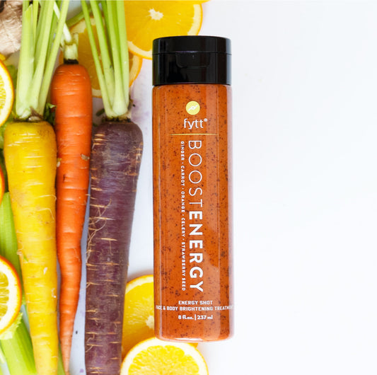 A jar of Brightening Exfoliating Mask from the brand "Cyan Ares" is placed on a surface alongside colorful carrots and sliced oranges, reminiscent of a refreshing Carrot Ginger Smoothie.