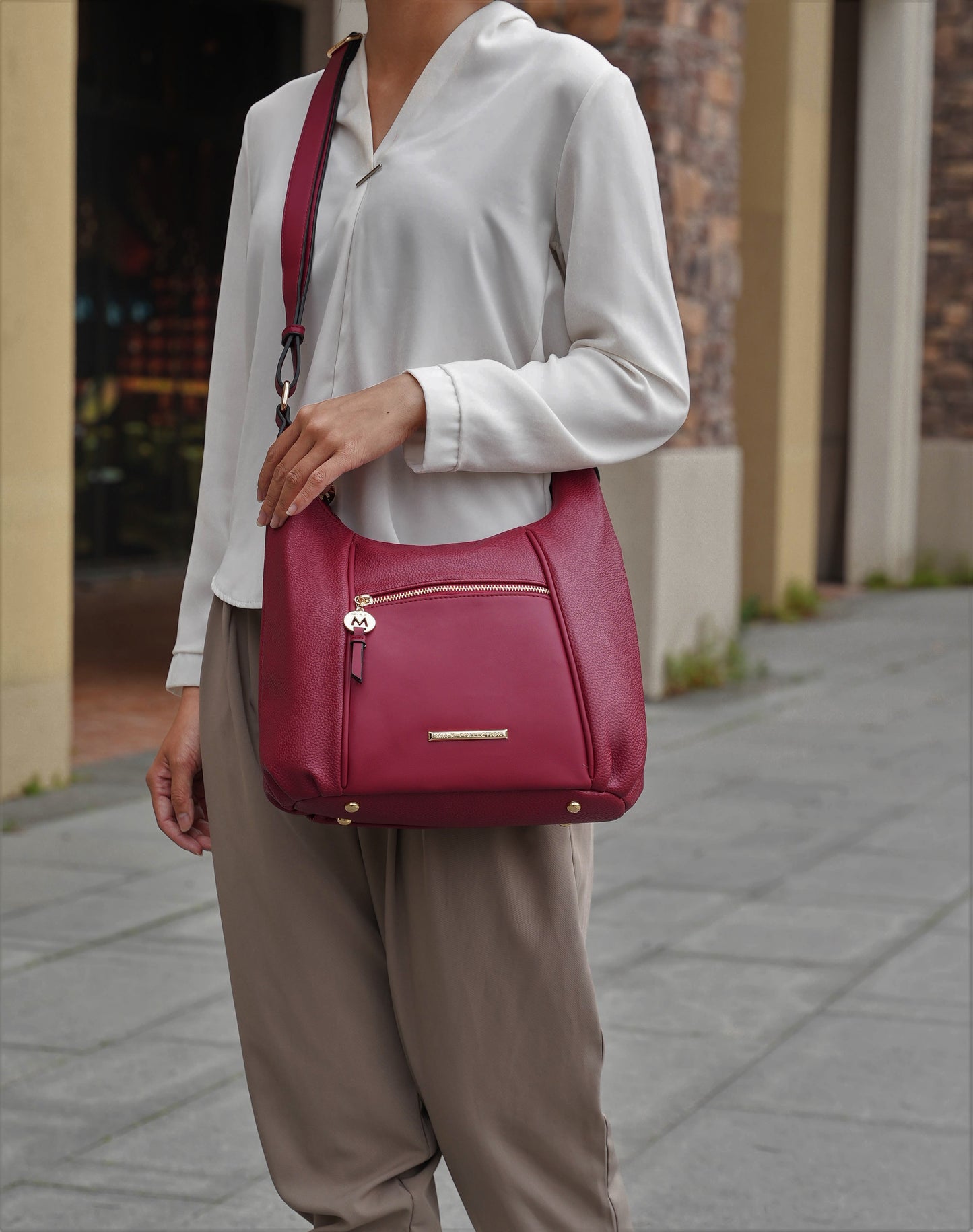 A fashion-forward woman carrying a Pink Orpheus Lavinia Vegan Leather Women’s Shoulder Bag with gold-tone embellishments.
