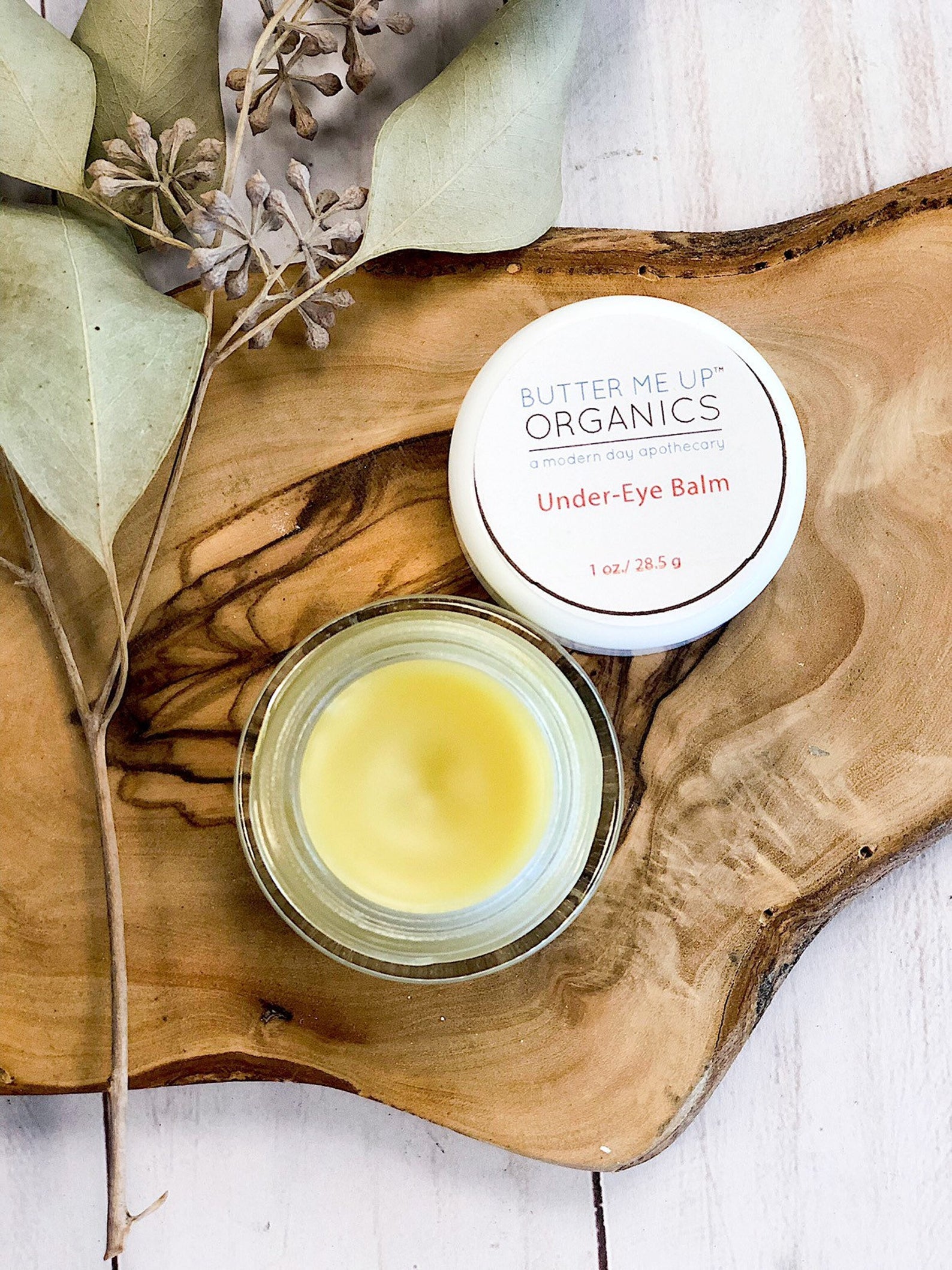A White Smokey Caffinated Under Eye Balm jar on a wooden cutting board, perfect for reducing puffiness and soothing under eyes. Made with caffeine-infused ingredients to revitalize tired skin.