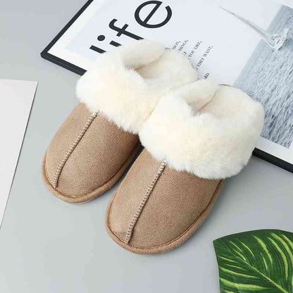 A pair of comfortable Trendsi Vegan Suede Center Seam Slippers made with vegan suede on a table next to a plant.