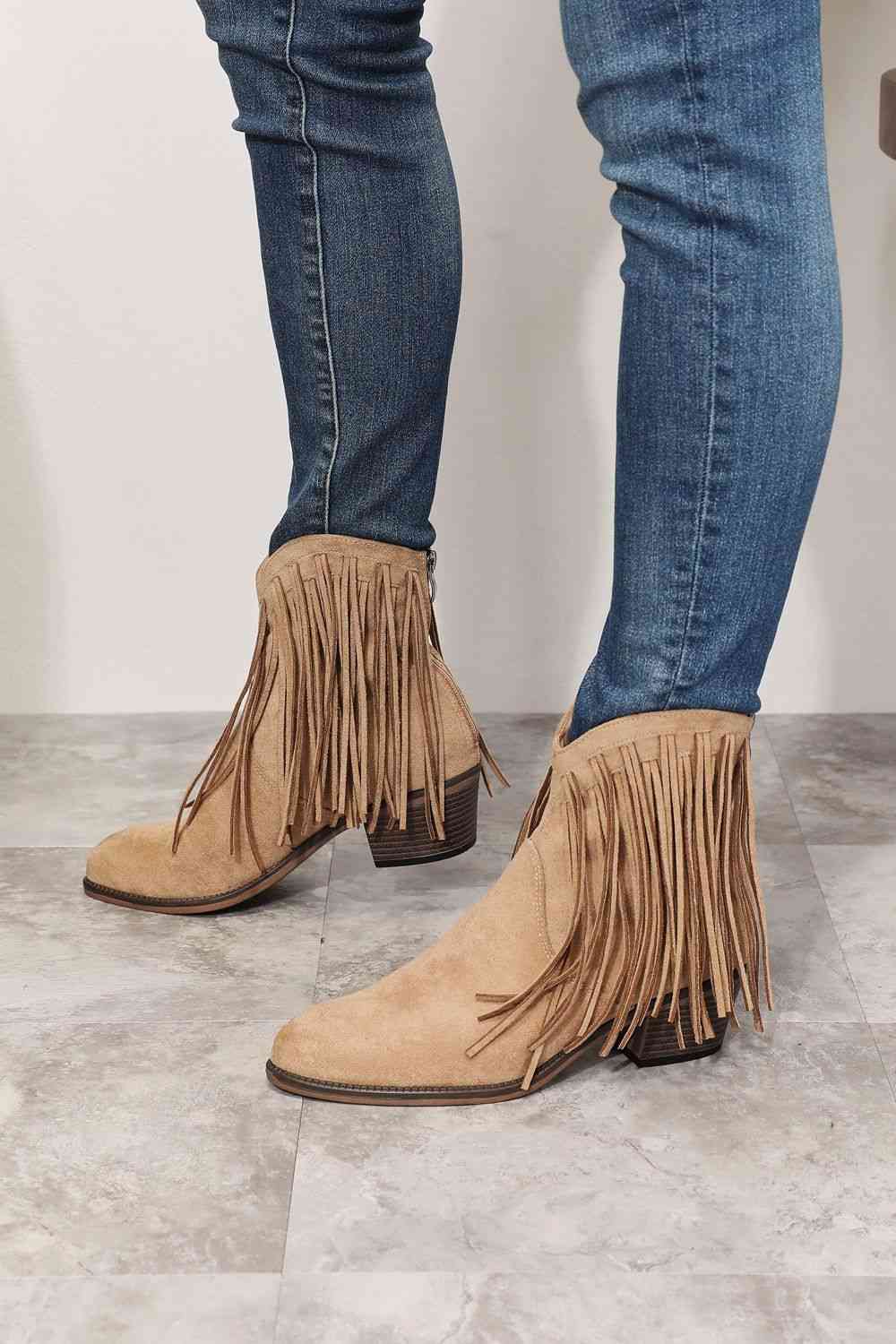 Person wearing blue jeans and brown Trendsi Legend Women's Fringe Cowboy Western Ankle Boots standing on a tiled floor.